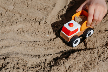 children's hand plays with a truck in the sand