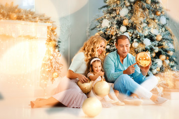 Family Christmas concept. Lovely family in bright clothes play near decorated Xmas tree on winter evening. Happy household with daughter on floor at home. Merry Christmas, happy New year. Trust, love.