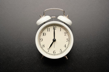 White vintage alarm clocks isolated on black table background.