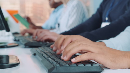 Close-up shot of operators hands typing on keyboard in modern office. People are busy working on...