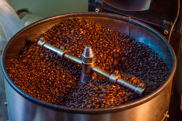 fresh roasted coffee bean over metal drum full of coffee bean, organic coffee roasted production