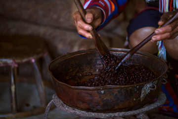 Hands of farmer demonstrates coffee roasting on old pan, organic coffee production