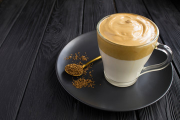 Dalgona coffee in the glass cup on  the black wooden  background. Closeup.