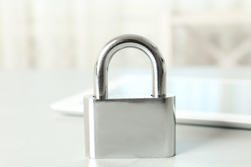 Fototapeta premium Metal lock and tablet on light grey table, closeup. Protection from cyber attack