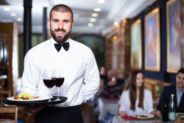 Professional waiter holding serving tray for restaurant guests