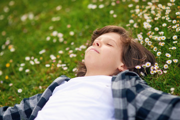 Portrait of young boy while lying in spring green garden