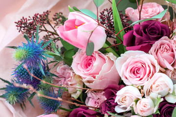 A closeup bouquet of roses and tulips decorated with leaves and twigs of other beautiful plants. Holiday concept. Flowers for Mother's Day.