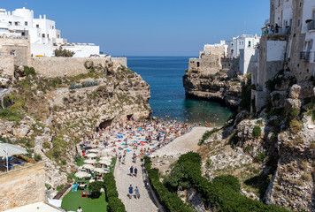  People relax and swimming on lovely beach Lama Monachile in Polignano a Mare, Adriatic Sea, Apulia, Bari province, Italy,