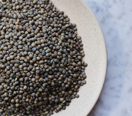 raw grains marble lentils on a white plate and marlbe background