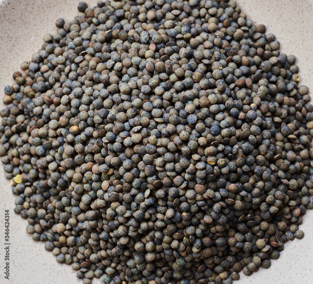 Wall mural raw grains marble lentils on a white plate and marlbe background