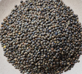 raw grains marble lentils on a white plate and marlbe background
