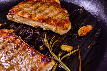 Roasted steaks with garlic, rosemary and spices in a cast iron grill pan