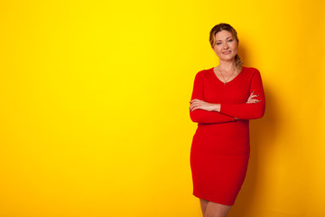 Fototapeta na wymiar beautiful woman in red dress on a yellow background for inscriptions