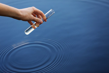 Water sample. Hand collects water to explore. Concept - water purity analysis, environment,...