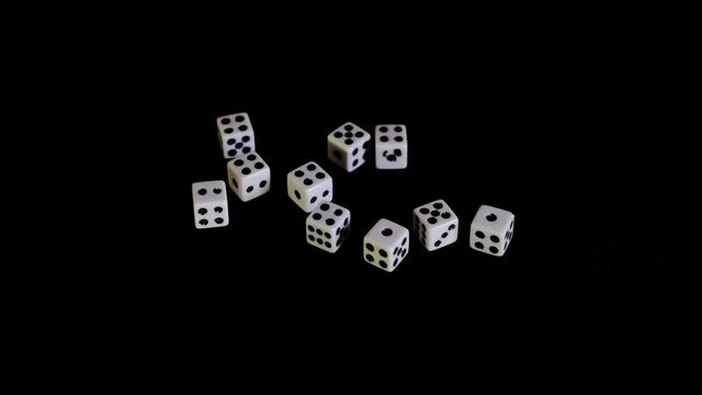 White cubes fall out, fly out on a black background for the game. The dice rotate on a black surface. Stops in sight. Concept of business and casino or gambling. Close-up. Slow motion