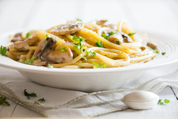 Spaghetti pasta with mushrooms, creamy sause and parsley on white