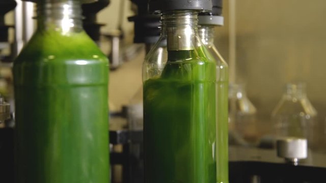 Automated filling machine in factory pours juice into plastic bottles on conveyor belt