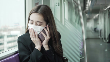 Fototapeta premium Businesswoman are using their smartphones while traveling on the train to work while the coronavirus is spreading.