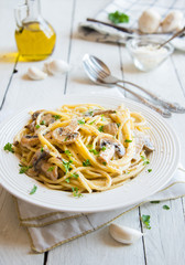 Spaghetti pasta with mushrooms, creamy sause and parsley on white