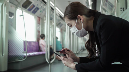 Businesswoman are using their smartphones while traveling on the train to work while the coronavirus is spreading.
