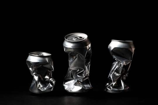 Crumpled aluminum cans soda or beer can garbage isolated on black background. Close up photo of aluminium cans. Aluminium beverage cans. Metal containers for packaging drinks.