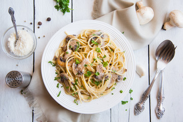 Spaghetti pasta with mushrooms, creamy sause and parsley on white