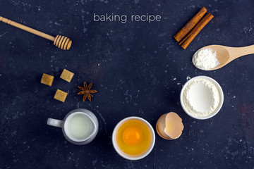 Frame of food Ingredients and utensils for cooking cake (flour, egg, milk, rolling pin, wooden spoon) on dark table. Food concept. Top view, flat lay layout, copy space for text. Baking background