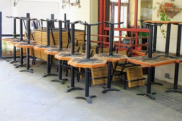 Athens, Greece, May 6 2020 - Tables and chairs stacked outside closed cafe-restaurant during the Coronavirus lockdown.
