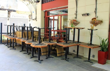 Athens, Greece, May 6 2020 - Tables and chairs stacked outside closed cafe-restaurant during the Coronavirus lockdown.