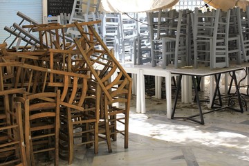 Athens, Greece, May 6 2020 - Tables and chairs stacked outside closed cafe-restaurant during the Coronavirus lockdown.