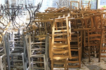 Athens, Greece, May 6 2020 - Tables and chairs stacked outside closed cafe-restaurant during the Coronavirus lockdown.