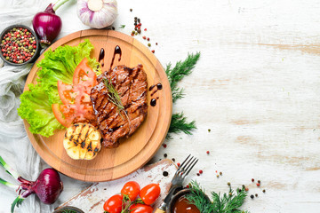 Juicy baked pork steak with vegetables on the board. Top view.