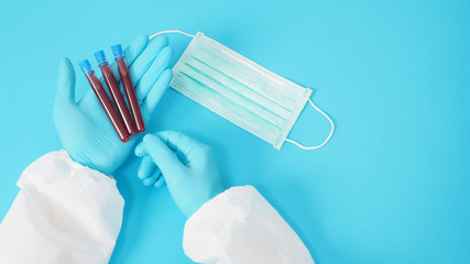 Male model with PPE suite and Hand wearing glove is holding face mask. Blood collection tubes on...