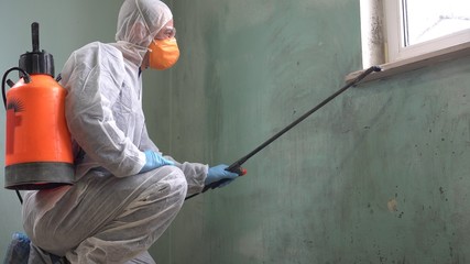 A man in a protective suit, glasses and a respirator sprays a disinfectant. Spraying disinfectants...