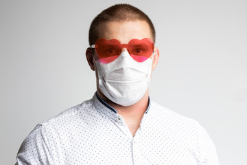 Male office worker in polo shirt, medical mask and bright sunglasses on a white isolated background. Concept photo: worker is afraid of news about coronovirus and believes in positive
