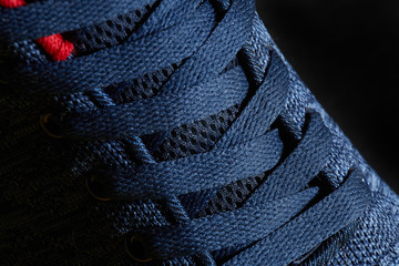 Blue tennis shoes or sneakers laces closeup macro on dark background.
