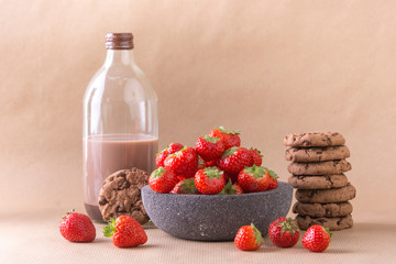 Cookies sweet biscuits American chocolate cake with chocolate cubes, fresh cocoa and red strawberries in bowl on pastel background.