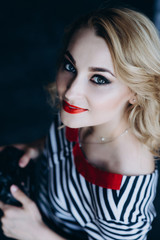 Young beautiful woman photographer with a camera in her hands in a photo studio. Women's work is a hobby. Soft selective focus. Toned photo.