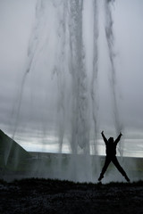 Person jumping up under the shower of Seljalandsfoss in Iceland
