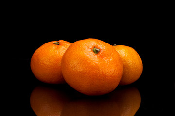 Ripe tangerines on a black background with reflection