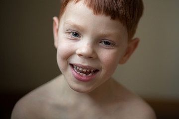 a strong portrait of a boy 5-6 years old, smiling, with red hair and freckles