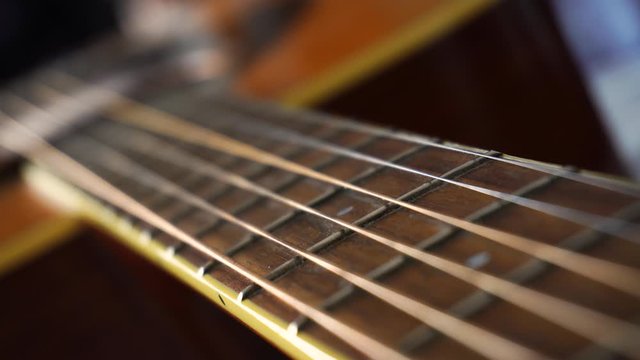 Close up macro on guitar strings or chords with very slow moving or panning. Musical instrument concept. Music and sound