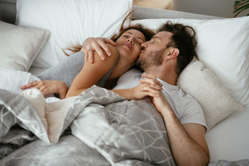 Fototapeta na wymiar Young loving couple in bed. Top view of happy couple relaxing in bed.