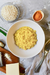 risotto with spices in a white plate on a gray background. ingredients for risotto Milanese recipe. delivery from the restaurant to order. rice, cheese, green onions, turmeric spices top view