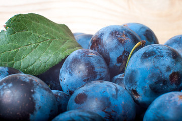 Ripe plums on a wood texture background