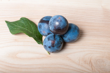 Ripe plums on a wood texture background