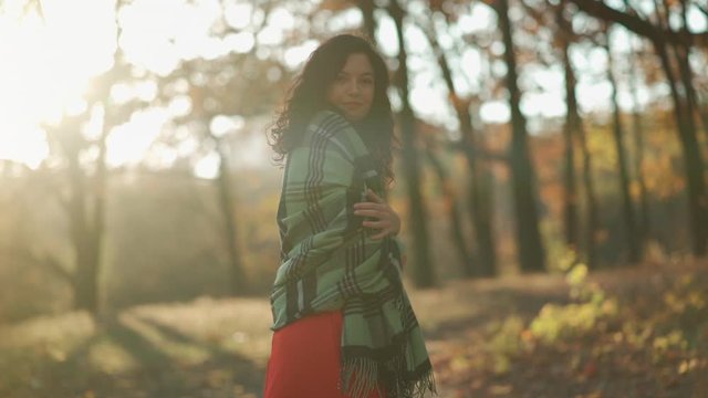 beautiful curly brunette female walking in autumn park and smiling