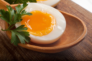 Boiled egg in a wooden spoon on a board