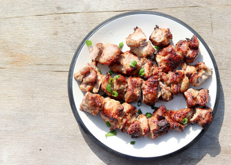 Grilled shish kebab on a white round plate on a aged wood background. Top view, flat lay