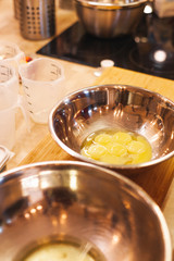 Metal bowls with eggs on the table in the kitchen with cooking utensils